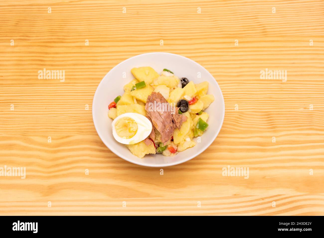 Köstlicher spanischer Landsalat mit gekochten Kartoffeln, Thunfisch in der Dose, gekochten Eiern, entkernten schwarzen Oliven und Paprika- und Zwiebelstückchen Stockfoto