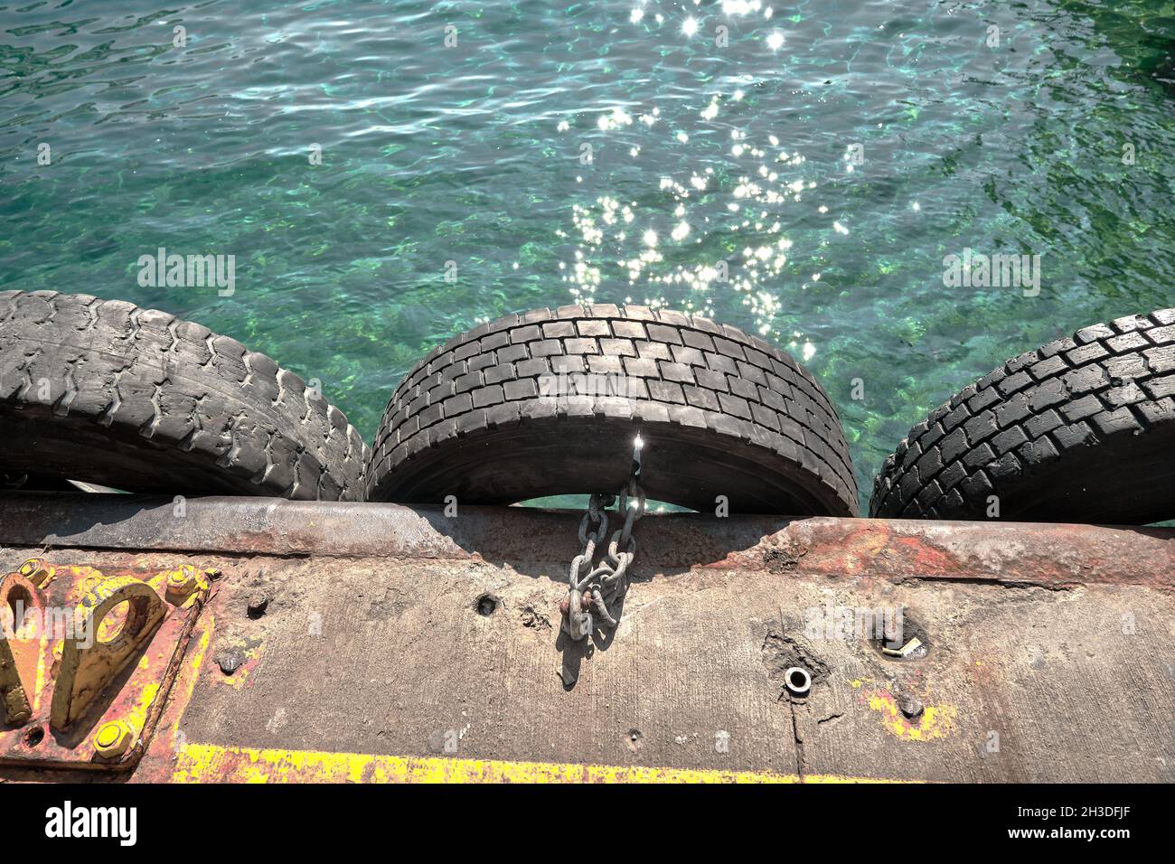 Alte Reifen hängen am Hafen von karakoy istanbul bosporus vorbei Mittel aus Metall Kette zum Verlegen neben etwas mit Türkis Farbe klares Wasser Stockfoto