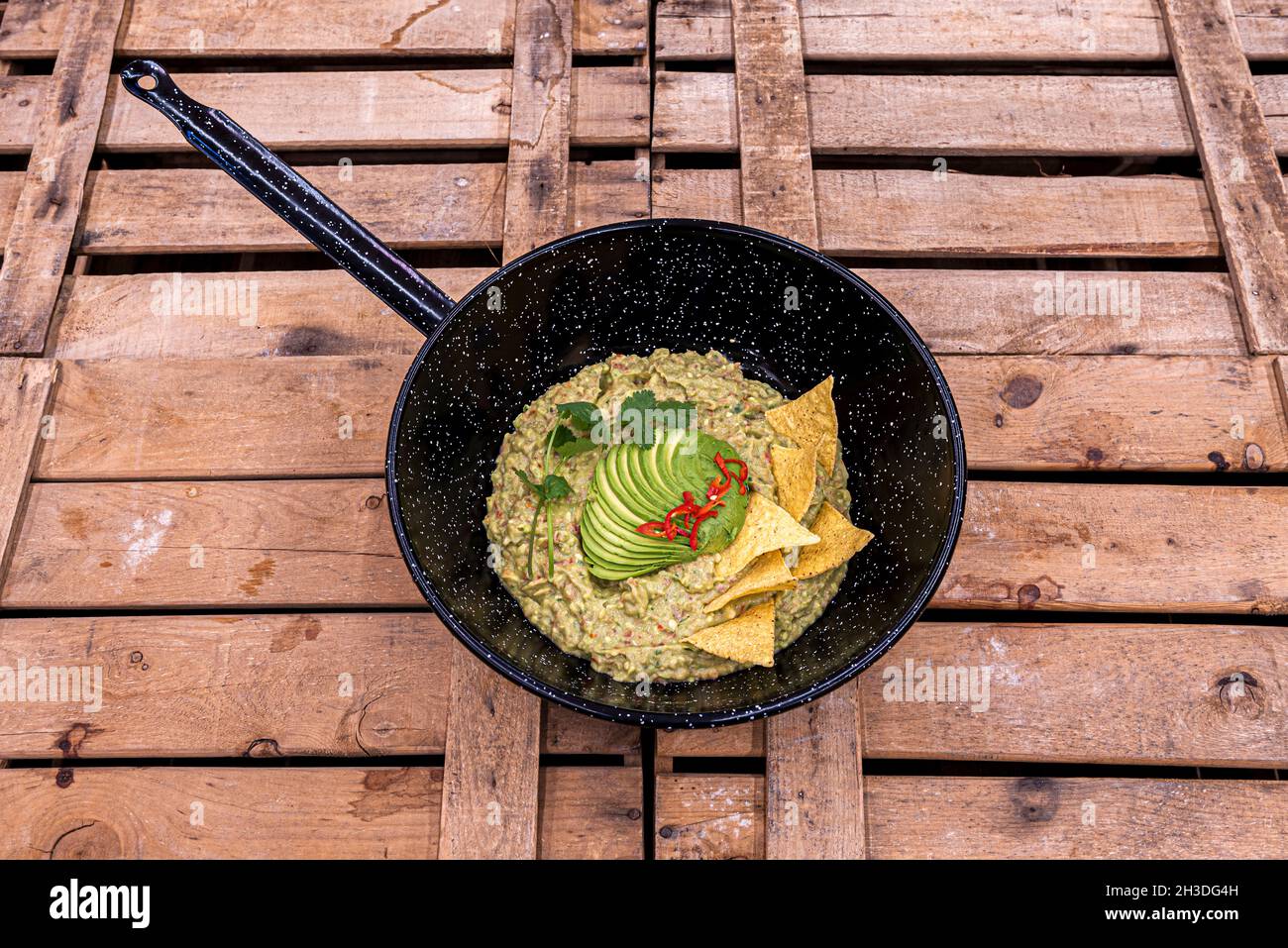 Eine mexikanische Guacamole mit Chips und reifen Guacamole, laminiert mit Petersilie, in der Pfanne teilen Stockfoto