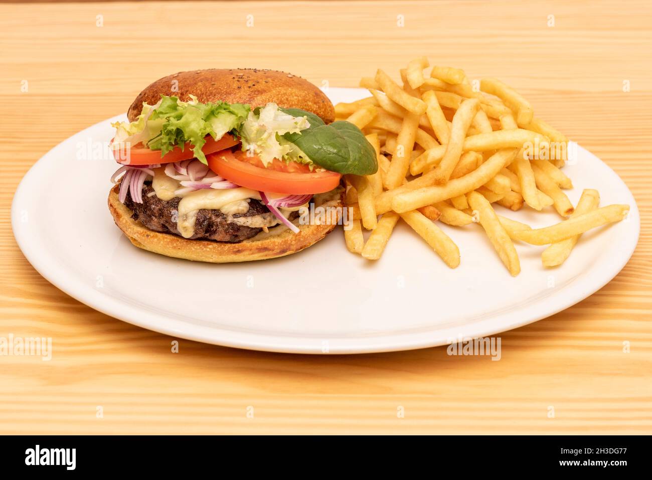Rinderburger mit Salatsprossen, geschmolzenem Käse, roten Zwiebeln und Tomatenscheiben, garniert mit Pommes frites Stockfoto