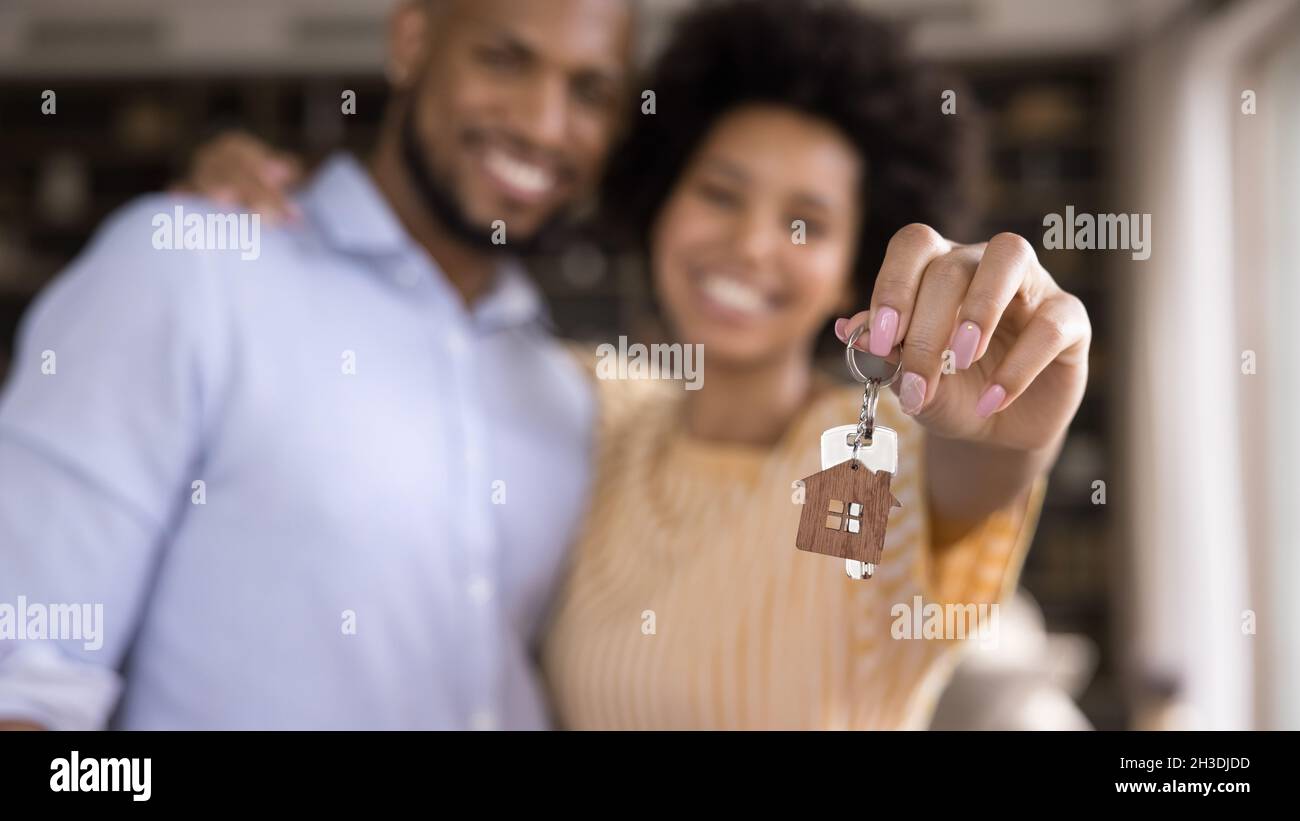Nahaufnahme der Schlüssel in den Händen des verschwommenen afrikanischen Paares. Stockfoto