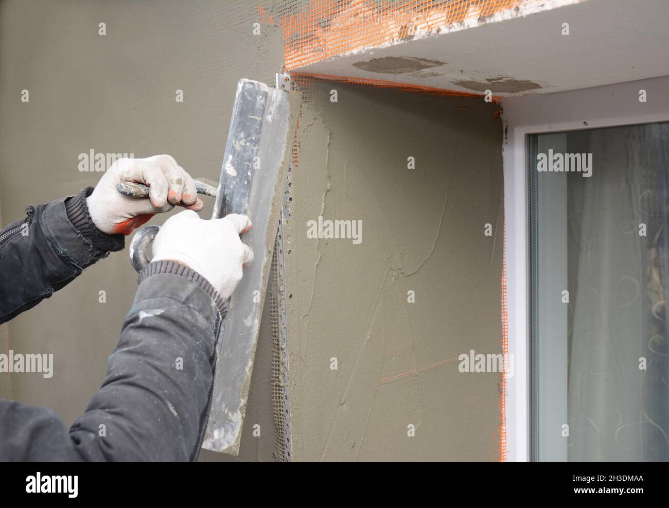Bauunternehmer Verputzen einer Wand mit Fiberglas-Mesh, Stuck, Gipsgewebe nach starrer Isolierung in Fensterbank Problembereich. Stockfoto