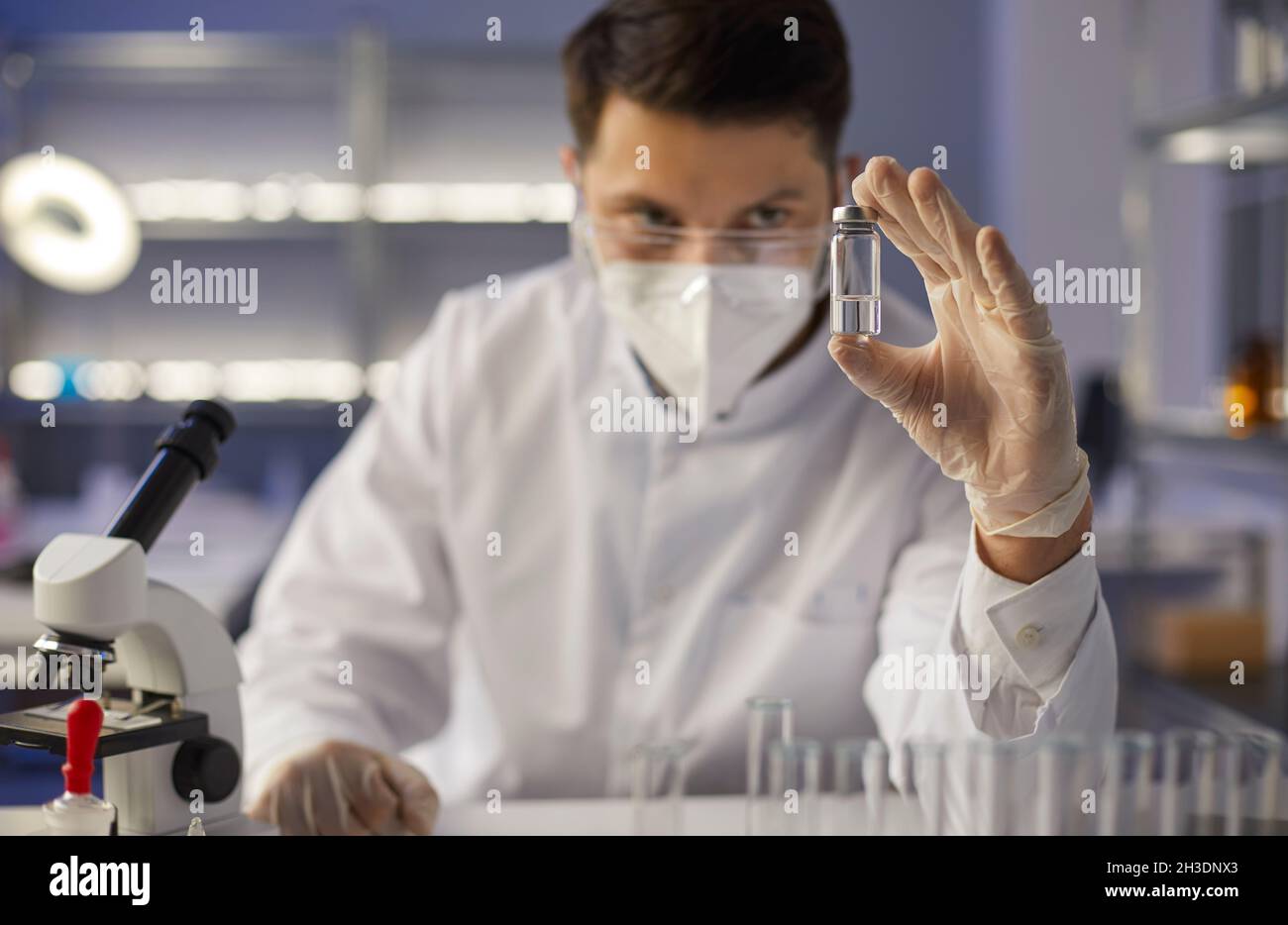 Fokussierter seriöser Arzt Wissenschaftler in einem medizinischen Labor betrachtet eine Glasampulle mit neuen Medikamenten. Stockfoto