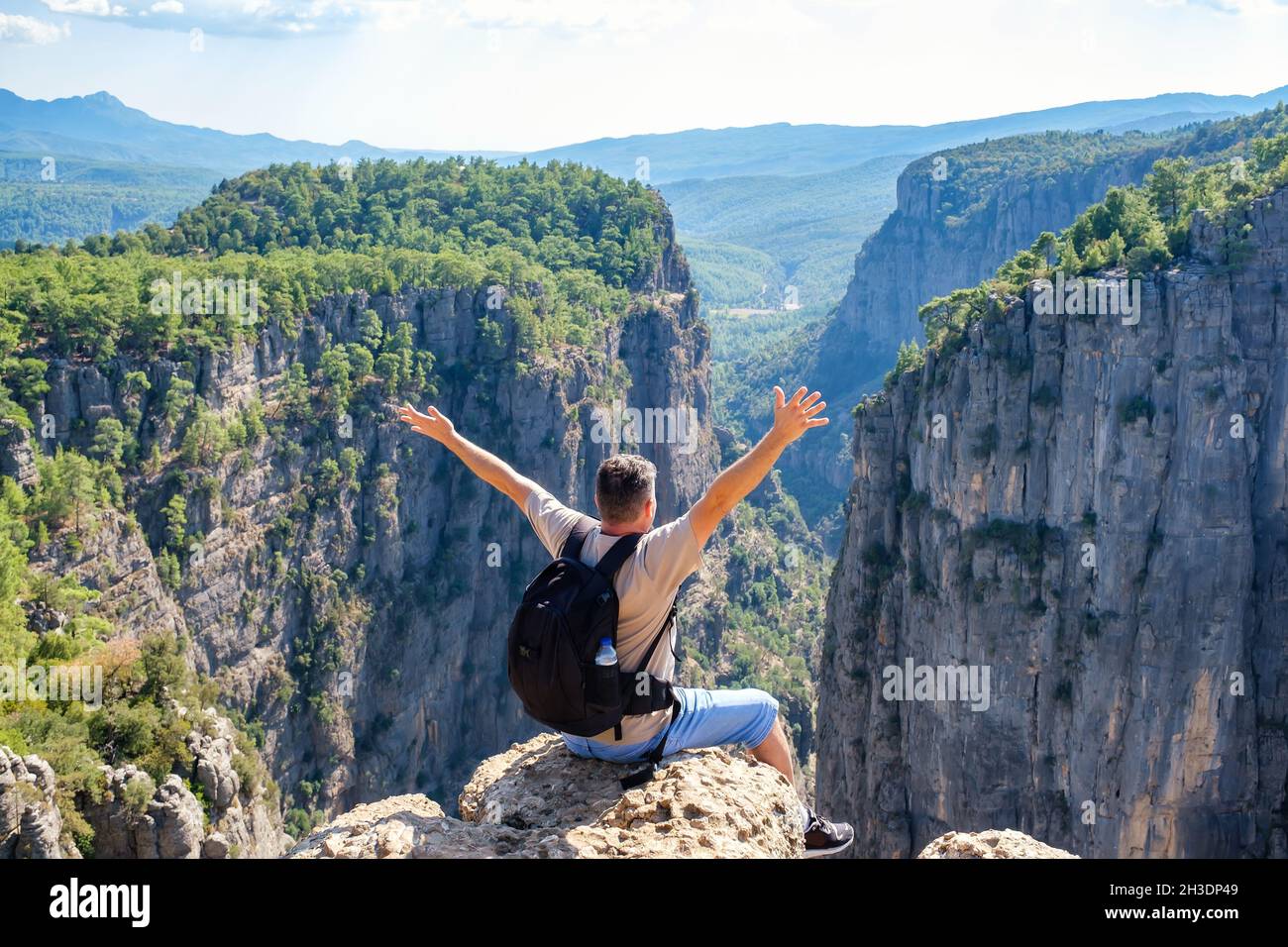 Nicht erkennbarer Mann, der am Rand der Klippe sitzt Stockfoto
