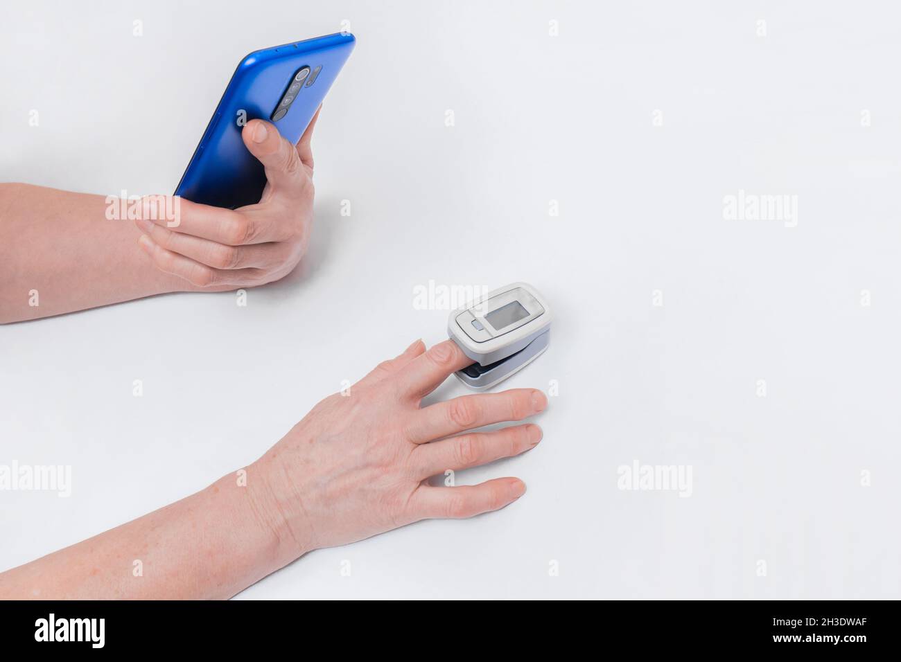 Die Hand einer älteren Frau hält ein Mobiltelefon oder Smartphone, misst mit einem modernen Medizinprodukt pu die Sättigung und den Sauerstoffgehalt im Blut Stockfoto