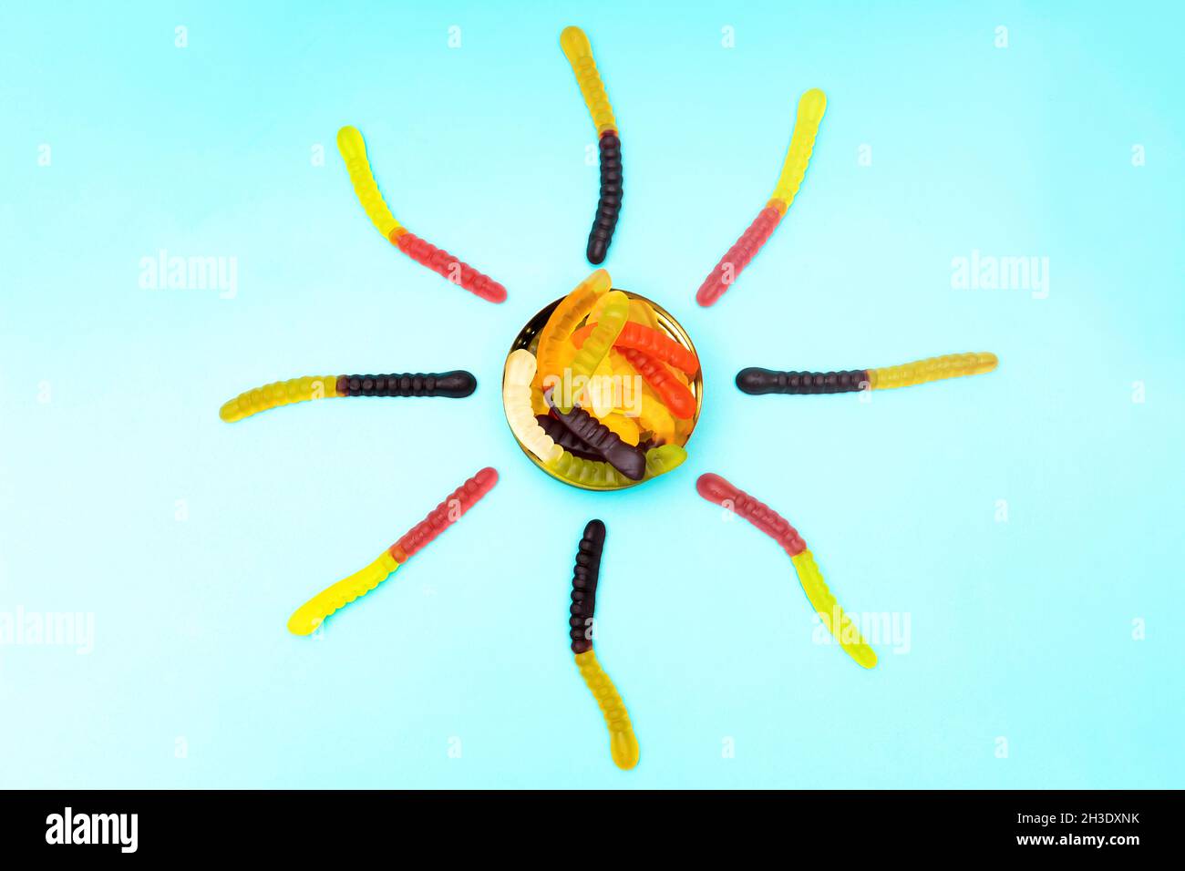 Sonnenform aus bunten Gummiwürmern auf blauem Hintergrund Stockfoto