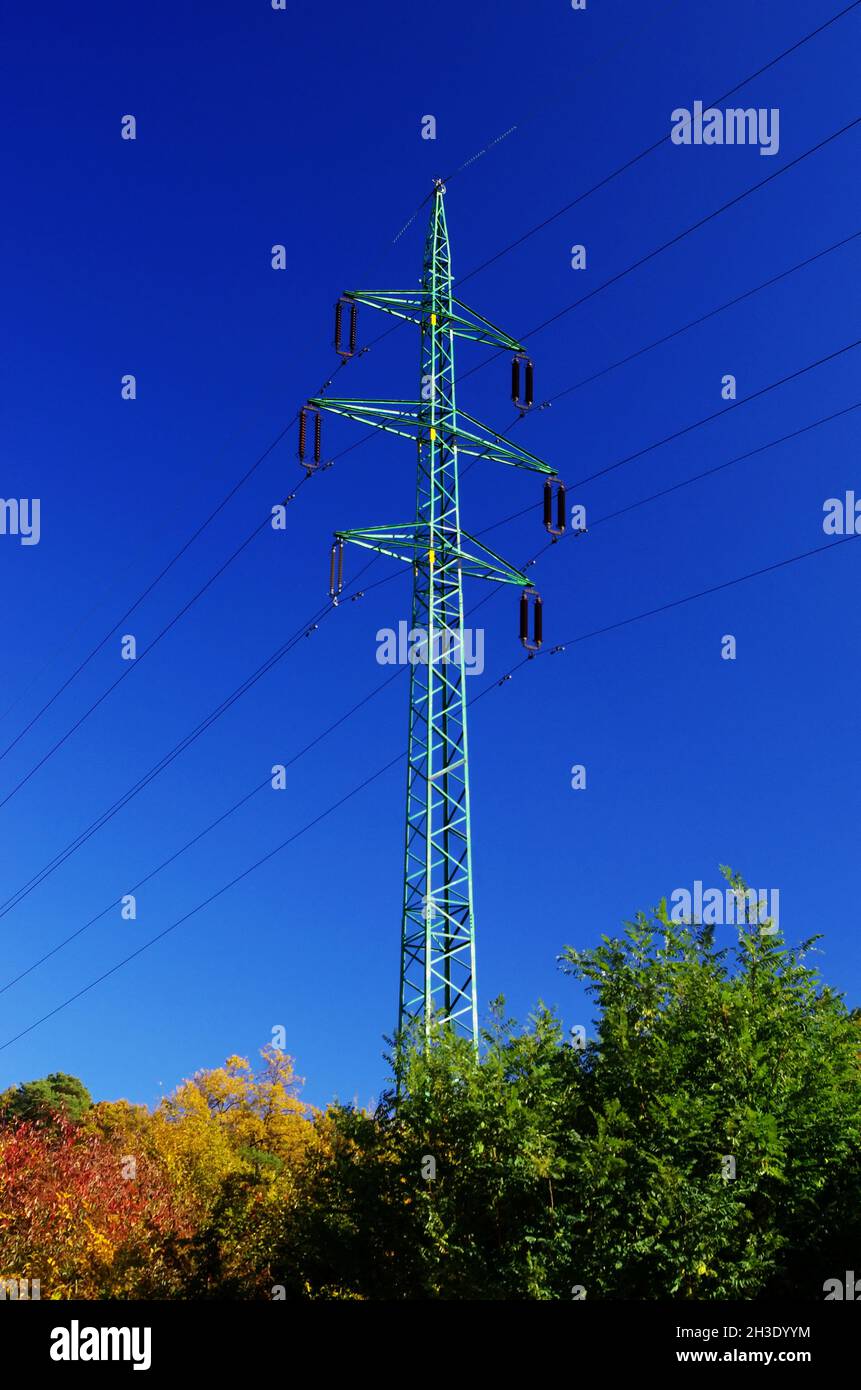 Hochspannungs-elektrische Türme und Linien mit schönem blauen Himmel über bunten Herbstbäumen. Eleetricity Türme. Hochspannungsübertragungsleitungen. Stockfoto