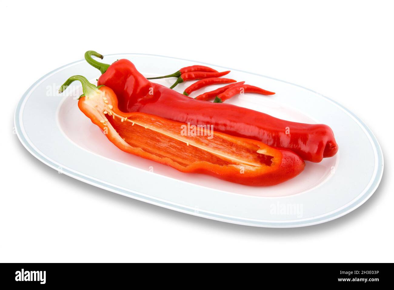 Chili (Capsicum spec. Rote Chilischoten auf einem Teller mit halbierten Paprika Stockfoto