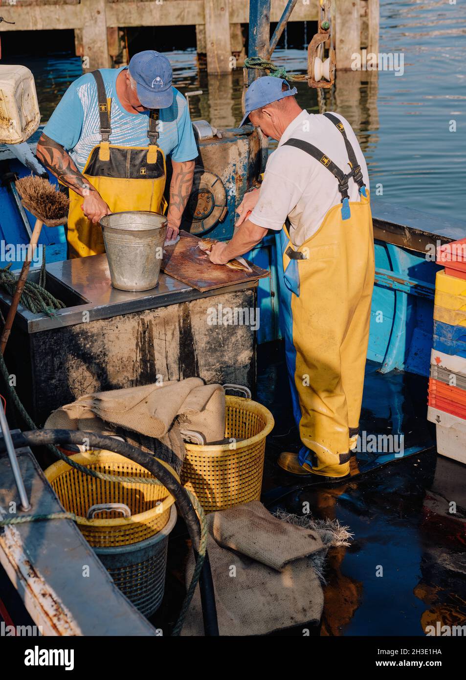 In Whitby North Yorkshire England, Großbritannien, arbeiten gewerbliche Fischer, die ihren Fang von weißem Fisch an Bord ihres Fischerbootes ausschaufeln Stockfoto