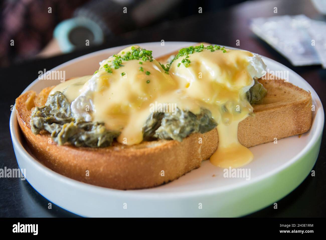 Traditionelle Eier Benedikt Florentiner mit pochierten Eiern. Rahmspinat, grüne Zwiebeln, Sauce Hollandaise und Muskatnuss, über einen brioch Brot Stockfoto