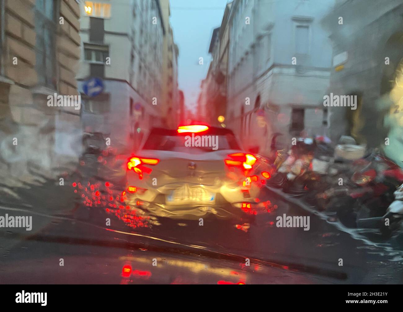 Regen auf der Straße mit Farbbeleuchtung an einem Verkehrsabend, Blick vom Auto auf der Straße, wenn es Regenzeit in der Stadt Wetter. Stockfoto