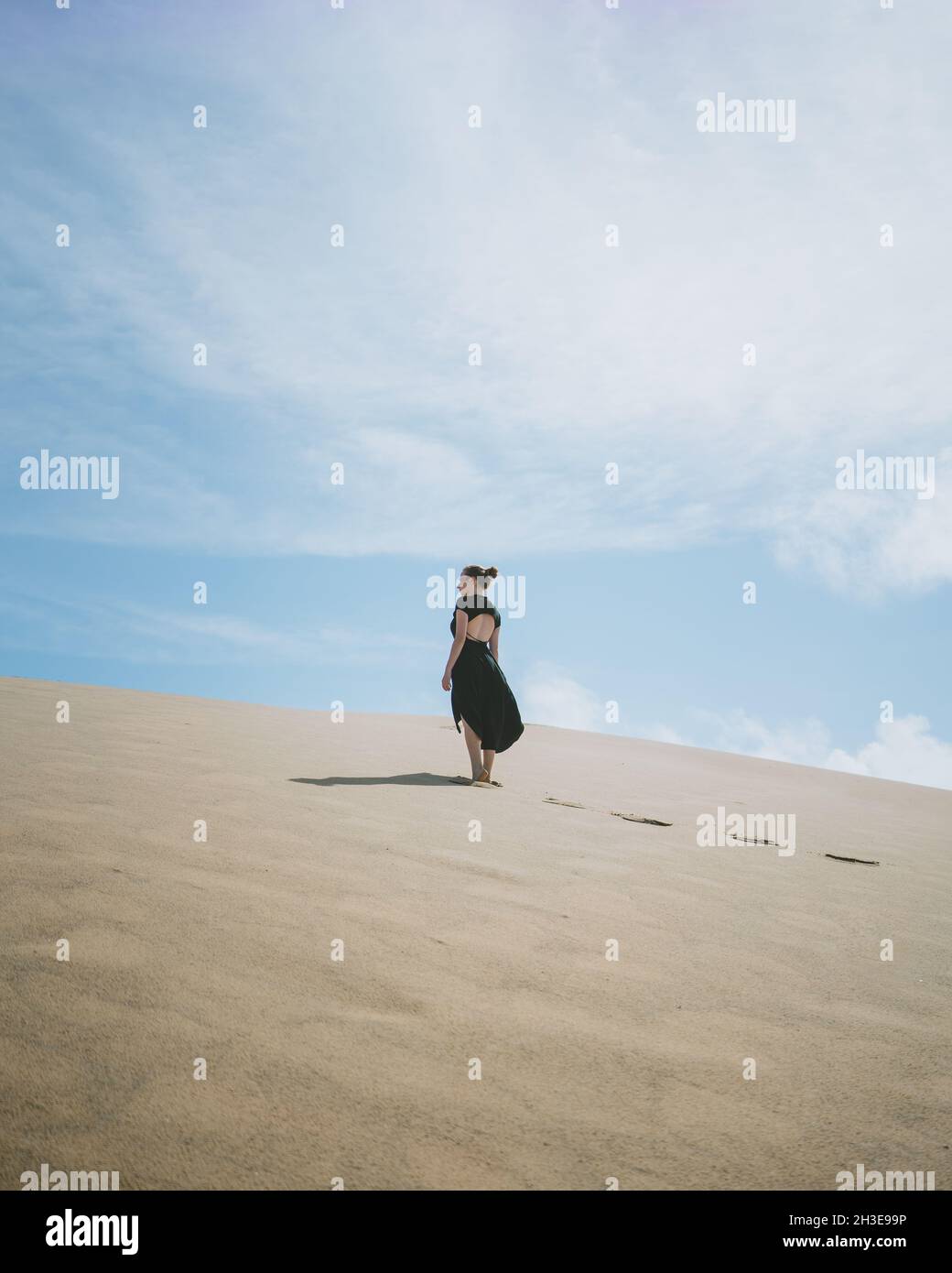 Fröhliche werdende Frau im Zierkleid sitzt auf Yoga-Ball Mit Kinderkleidung gegen Kommode im Zimmer Stockfoto