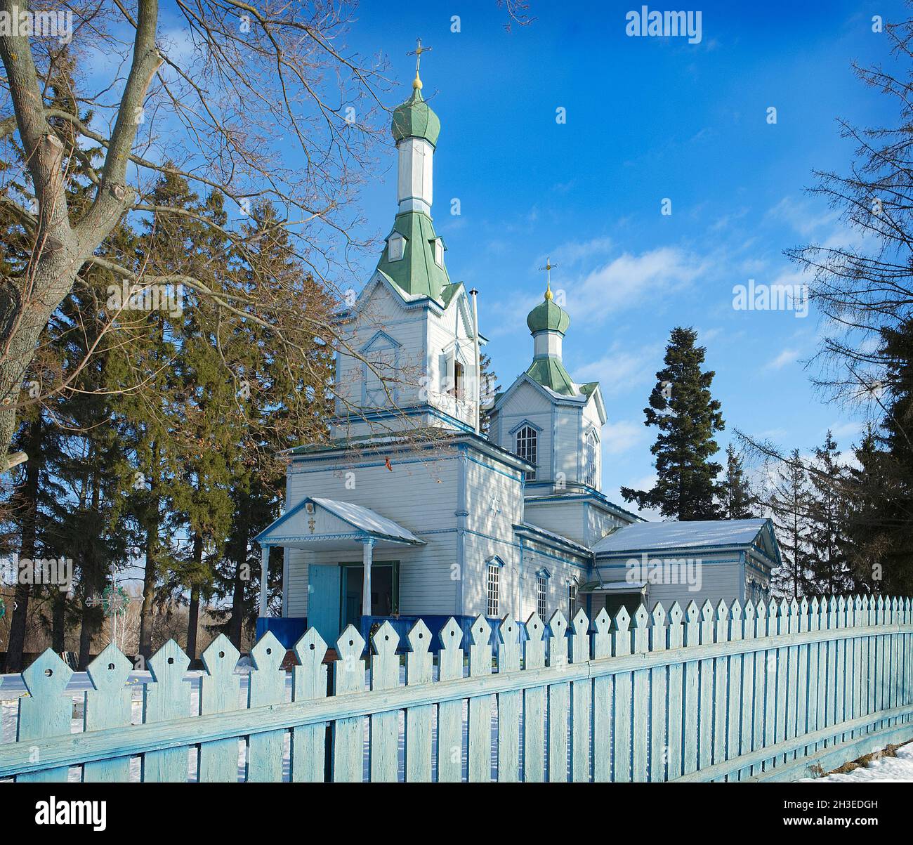 Kleine weiße Holzkirche mit Bäumen und blauem Himmel Stockfoto