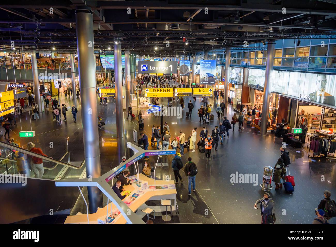 Flughafen Schiphol, Niederlande - 17. Oktober 2021: Überfüllte Abfluglounge mit Geschäften und Restaurants in der Schengen-Zone des Terminals Stockfoto