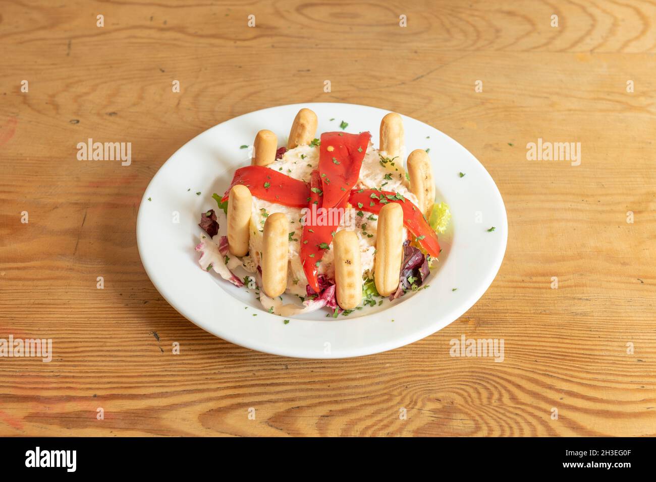 Russischer Salat mit gekochtem Ei und Kartoffeln, Mayonnaise, geriebener Karotte, Paprika, Spitzen von Landbrot und Petersilie, serviert als spanische Tapas Stockfoto