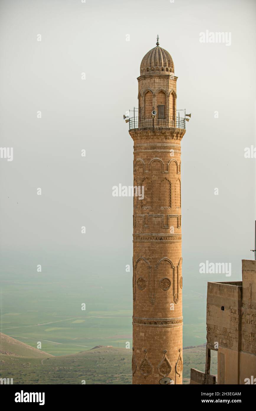 Antikes Minarett aus Sandsteinziegeln mit Lautsprechern und Flachreliefs eines Tages mit Staub in der Umgebung Stockfoto