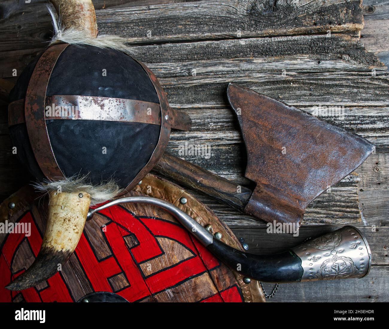 Kampf Axt gehörnten Helm Signalhorn und Schild mit viking Runen auf rauen Holztisch Draufsicht bedeckt Stockfoto