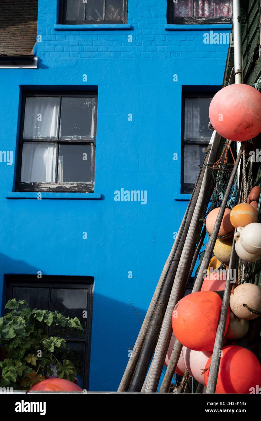 Hastings, Oktober 2021 Blaues gemaltes Haus mit Fischerbooten Stockfoto