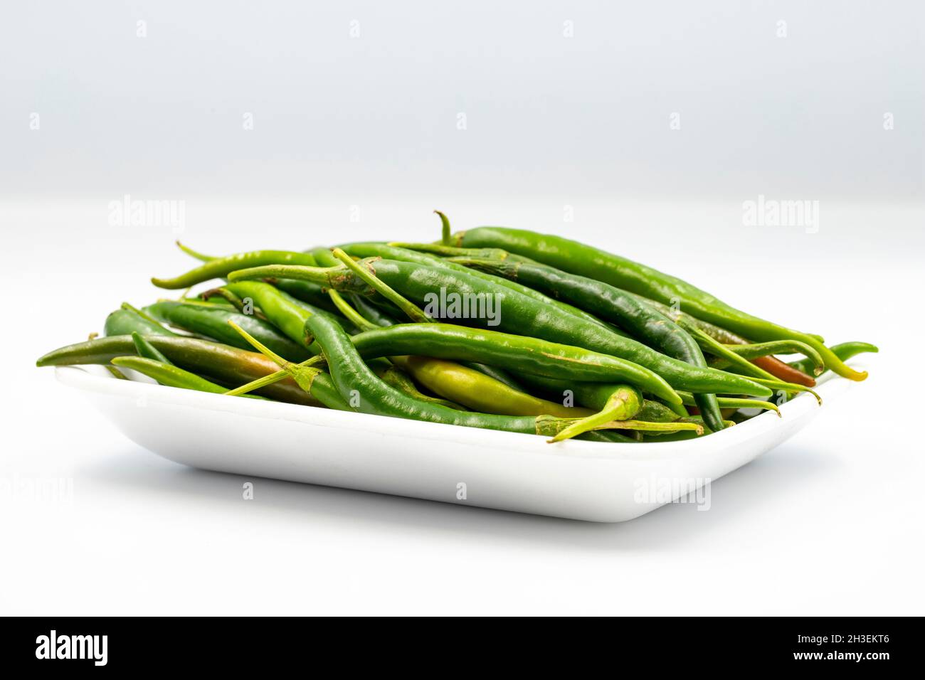 Päckchen grüne Chilischoten auf weißem Hintergrund mit Schatten. Nahaufnahme Stockfoto