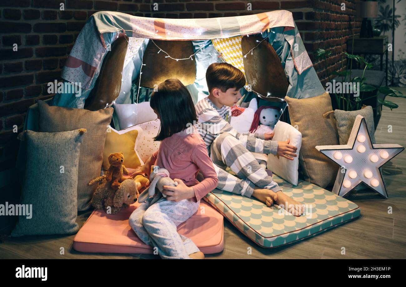 Kinder bereiten Zelt mit Stühlen und Bettwäsche Stockfoto