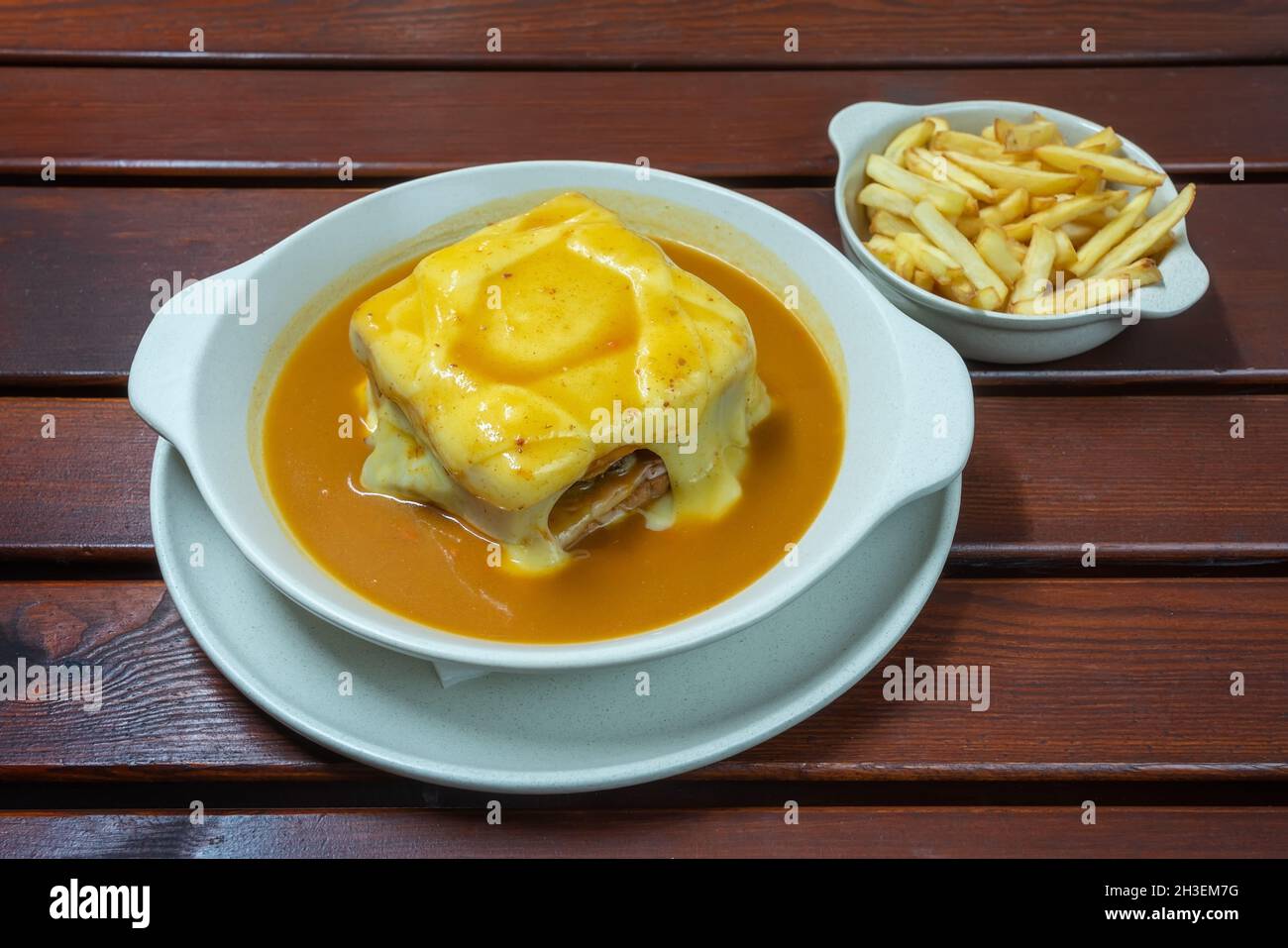 Francesinha ist ein portugiesisches Sandwich, das aus Brot, Schinken, Linguica, Wurst, Steak, und mit Käse und Biersauce bedeckt. Nahaufnahme Stockfoto