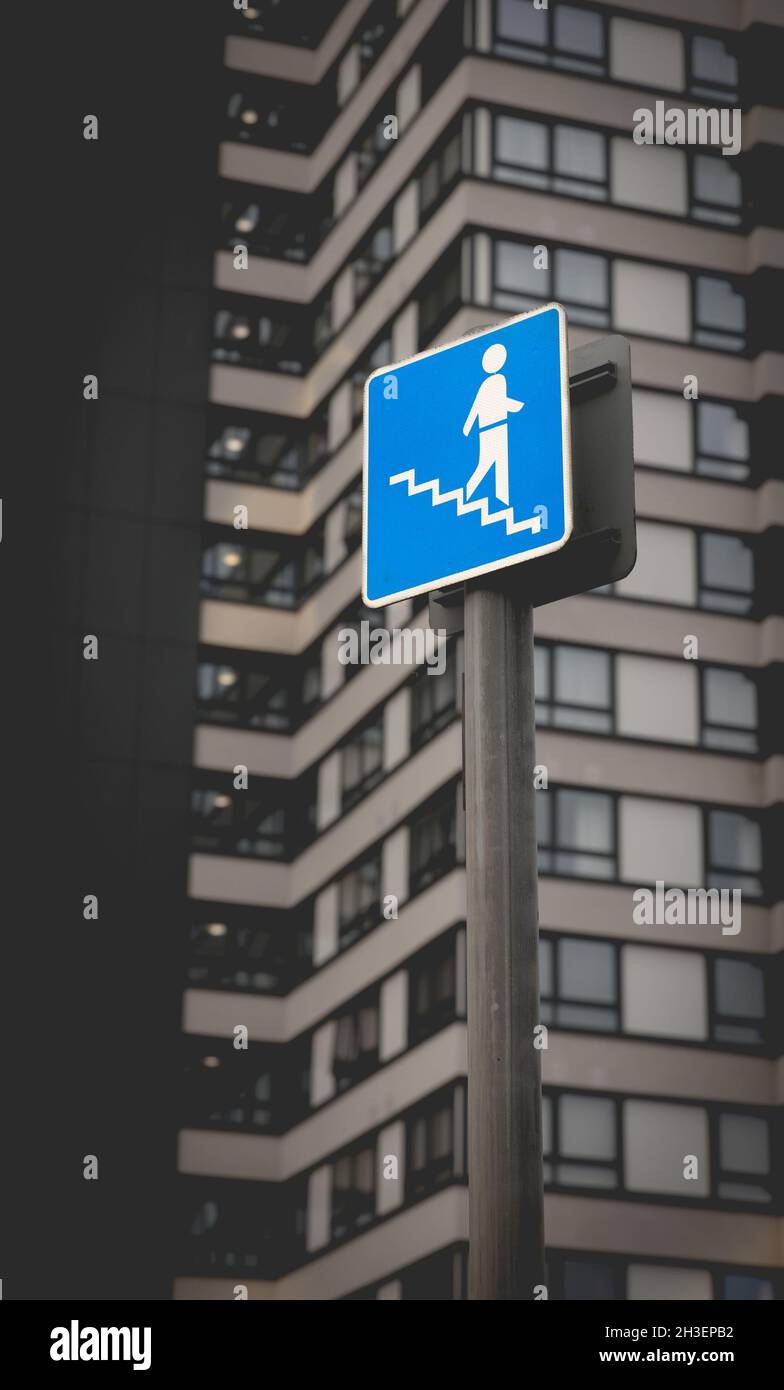 Ein blaues Warnschild in einer städtischen Umgebung, das die Menschen über die Notwendigkeit informiert, Treppen oder Stufen zu benutzen Stockfoto