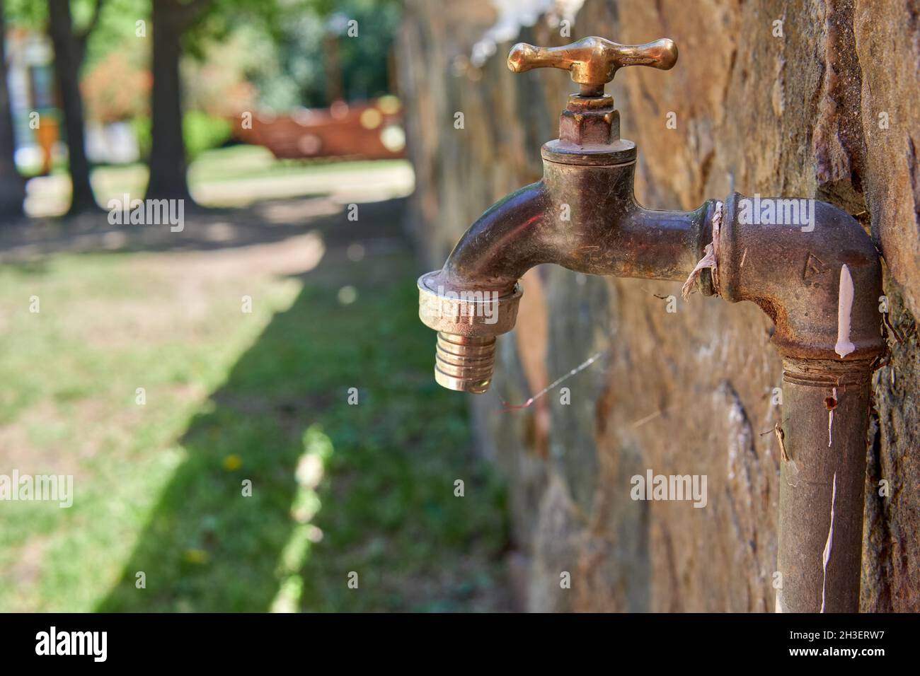 Nahaufnahme Profil eines Bronze-Wasserhahn im Freien. Verschwommener Hintergrund, selektiver Fokus. Horizontal Stockfoto