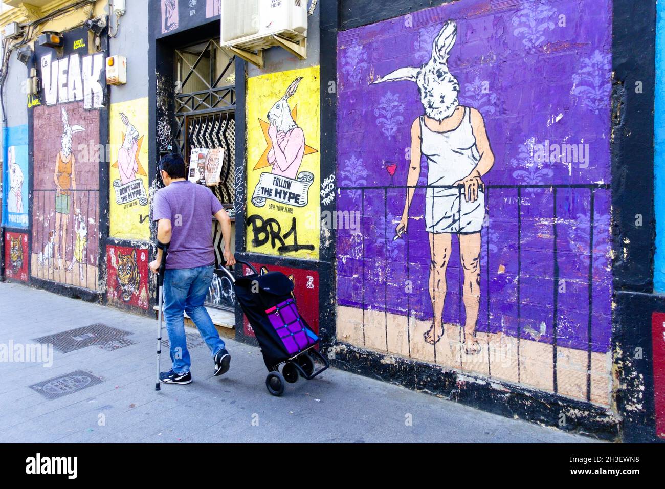 Straßenkunst Spanien Wandmalerei Valencia Russafa Mann zu Fuß Einkaufstasche männliche Person zu Fuß allein Stadt Straße Valencia Ruzafa Stadt Mann zu Fuß herum Stockfoto