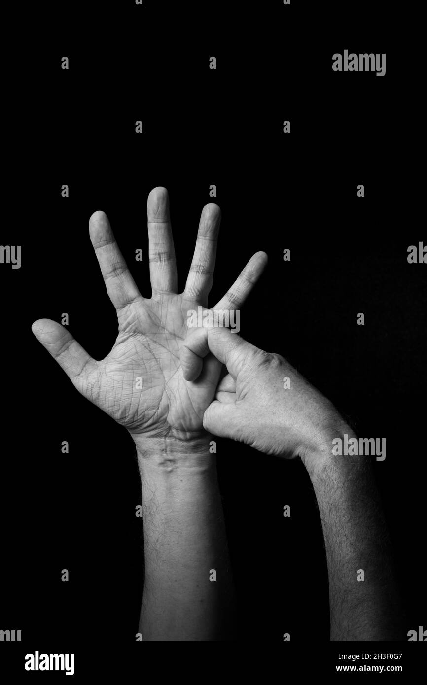 Dramatisches Schwarzweiß-Bild der männlichen Hand Fingerbuchstabierung BSL britische Gebärdensprache Buchstaben R isoliert vor dunklem Hintergrund Stockfoto