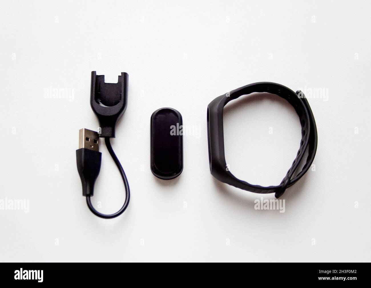 Schwarzes Fitness Tracker Gerät Modell mit Lade-USB-Kabel und Armband isoliert auf weißem Hintergrund Stockfoto