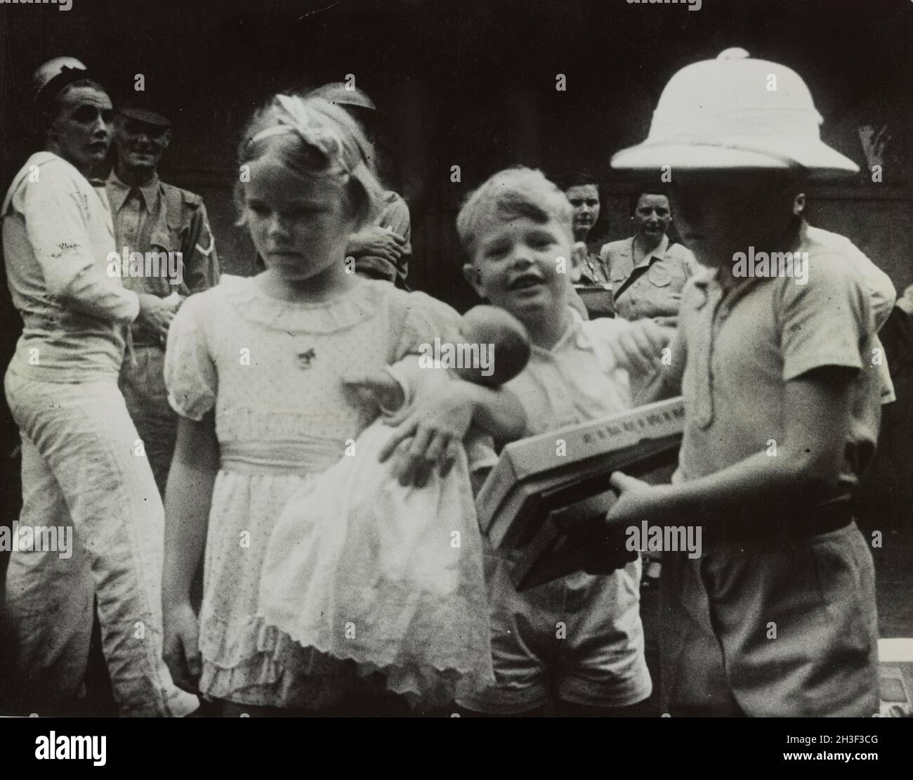 Ein Vintage-Foto um den Februar 1942, das britische Kinder zeigt, die vor der japanischen Invasion von Malaya und dem Fall von Singapur per Schiff aus Singapur evakuiert wurden. Britische Matrosen und Soldaten erscheinen im Hintergrund. Stockfoto