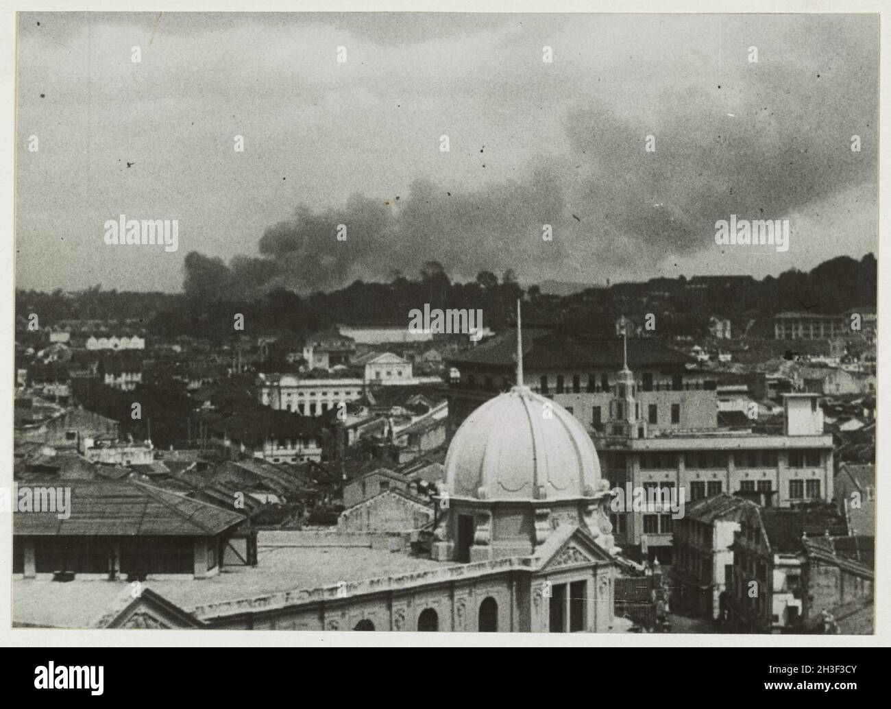 Ein Vintage-Foto um den Februar 1942, das den Rauch zeigt, der während eines Luftangriffs der japanischen Luftwaffe während der Invasion von Malaya und des Sturzes von Singapur über die Stadt Singapur aufsteigt. Stockfoto