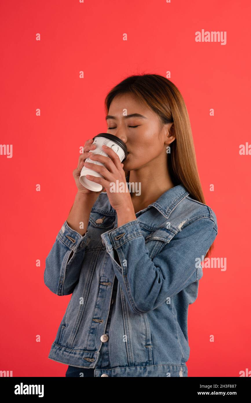 Junge attraktive asiatische Mädchen trinken Kaffee im Studio Stockfoto