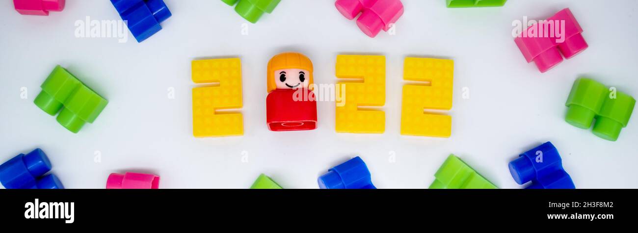 Banner bunte Bausteine, Spielzeug Kunststoff Figur: Mädchen in 2022 Zahlen auf weißem Hintergrund. Stockfoto