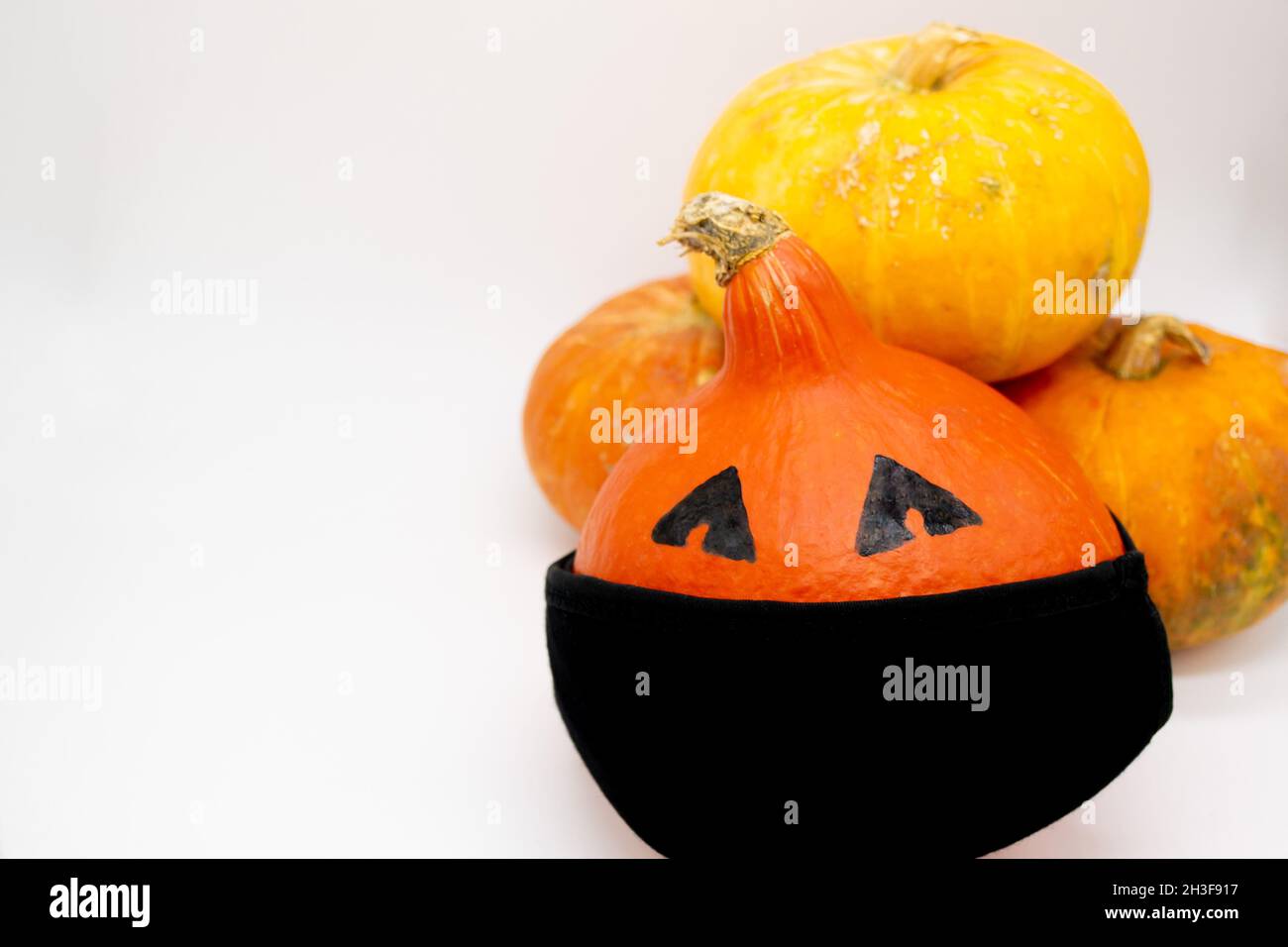 Halloween und Covid-19 : Orange Kürbisse, einer mit Augen in einer schwarzen Maske steht auf den anderen. Boo. Stockfoto