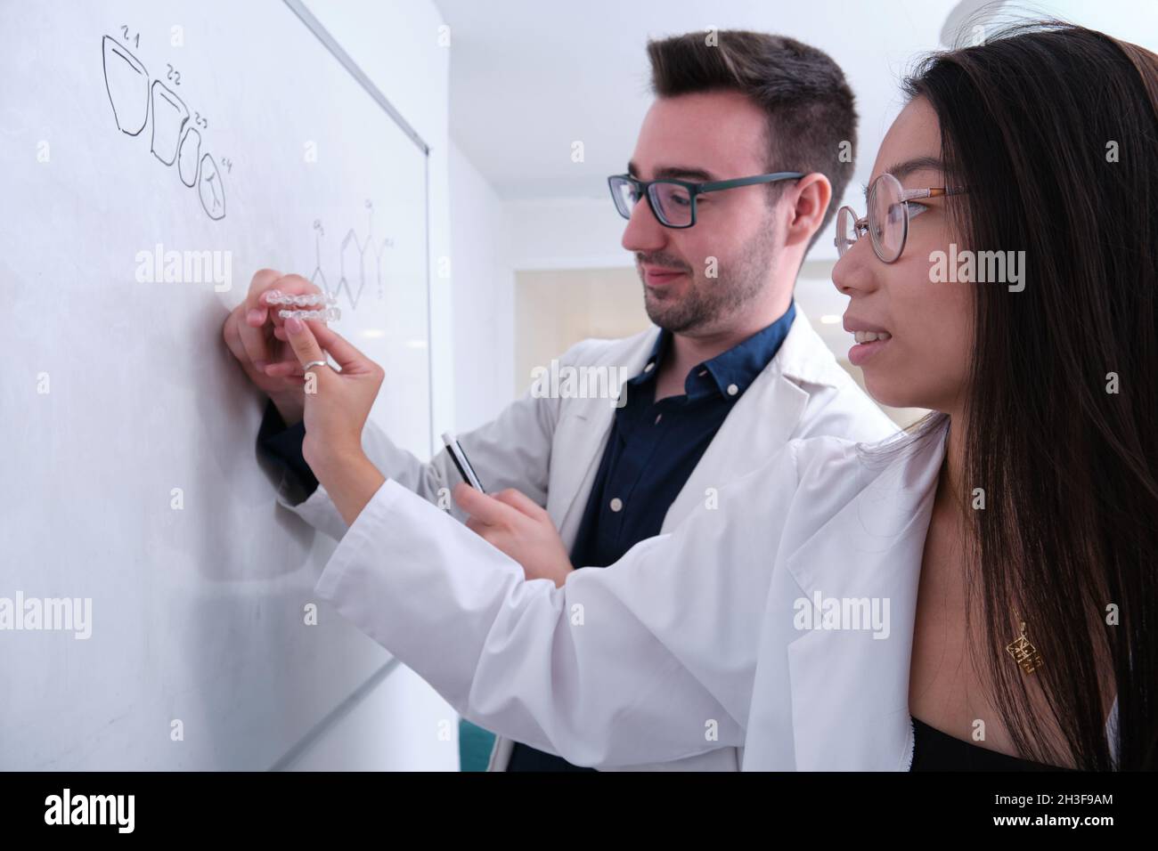 Zwei Zahnarztforscher untersuchen die Zahnanatomie auf einem Whiteboard. Stockfoto