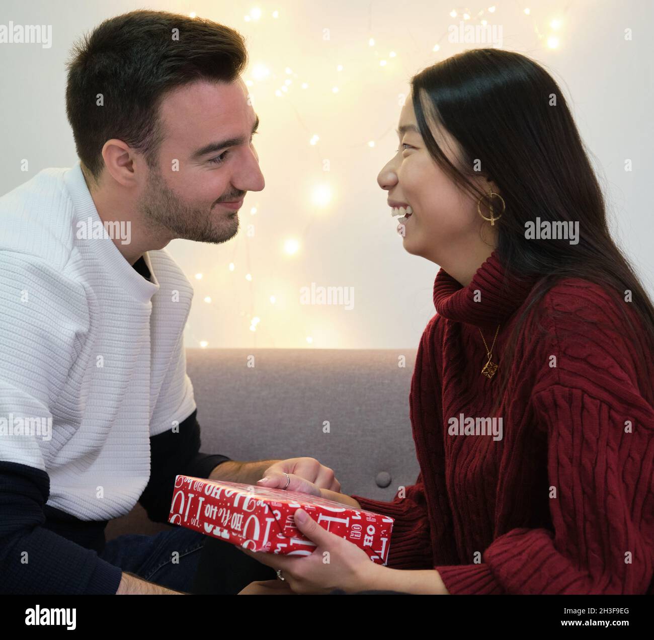 Junge, multirassische, glückliche Paare tauschen Weihnachtsgeschenke aus. Stockfoto