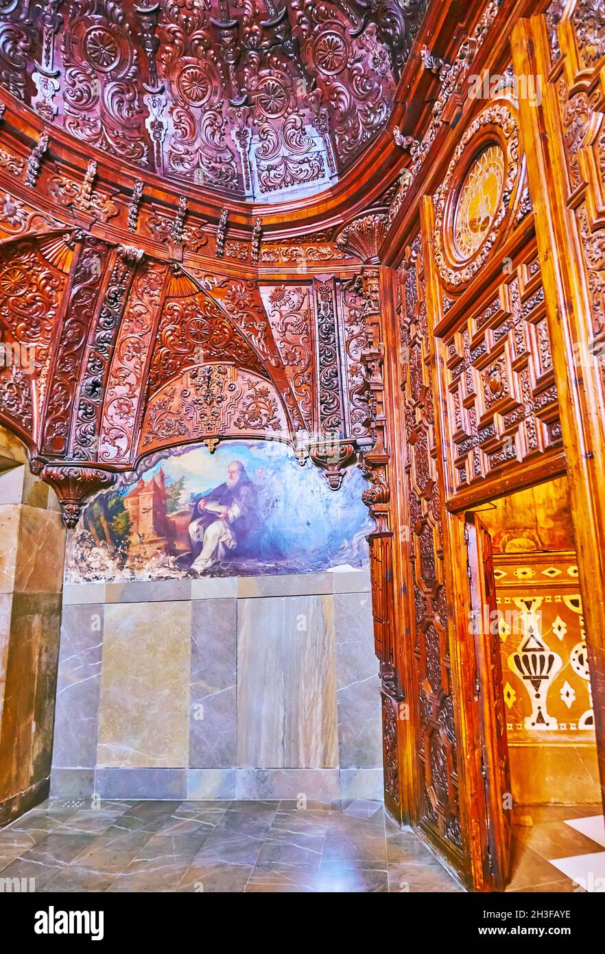 GRANADA, SPANIEN - 27. SEPTEMBER 2019: Der geschnitzte hölzerne Eingangskorridor der Basilika San Juan de Dios ist mit mittelalterlichen Gemälden an der Wand geschmückt, Stockfoto