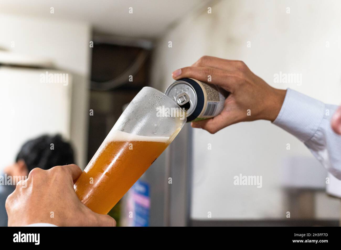 Gießt Bier von Hand aus einer Dose in ein Glas Stockfoto
