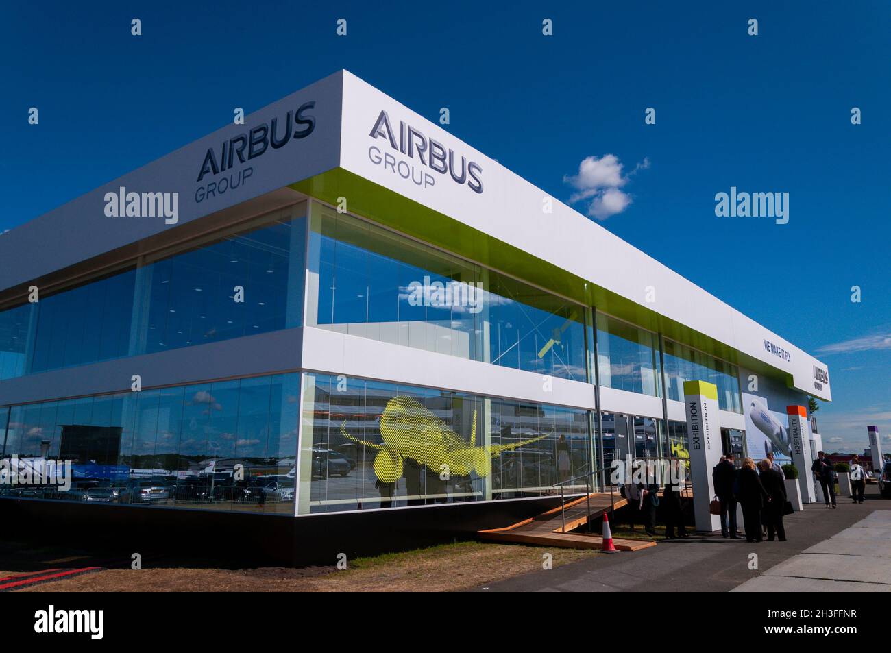 Chalet der Airbus Group auf der Farnborough International Airshow 2014 mit Außenvertretern. Markenlogo und Flugzeug-Grafik unter blauem Himmel Stockfoto