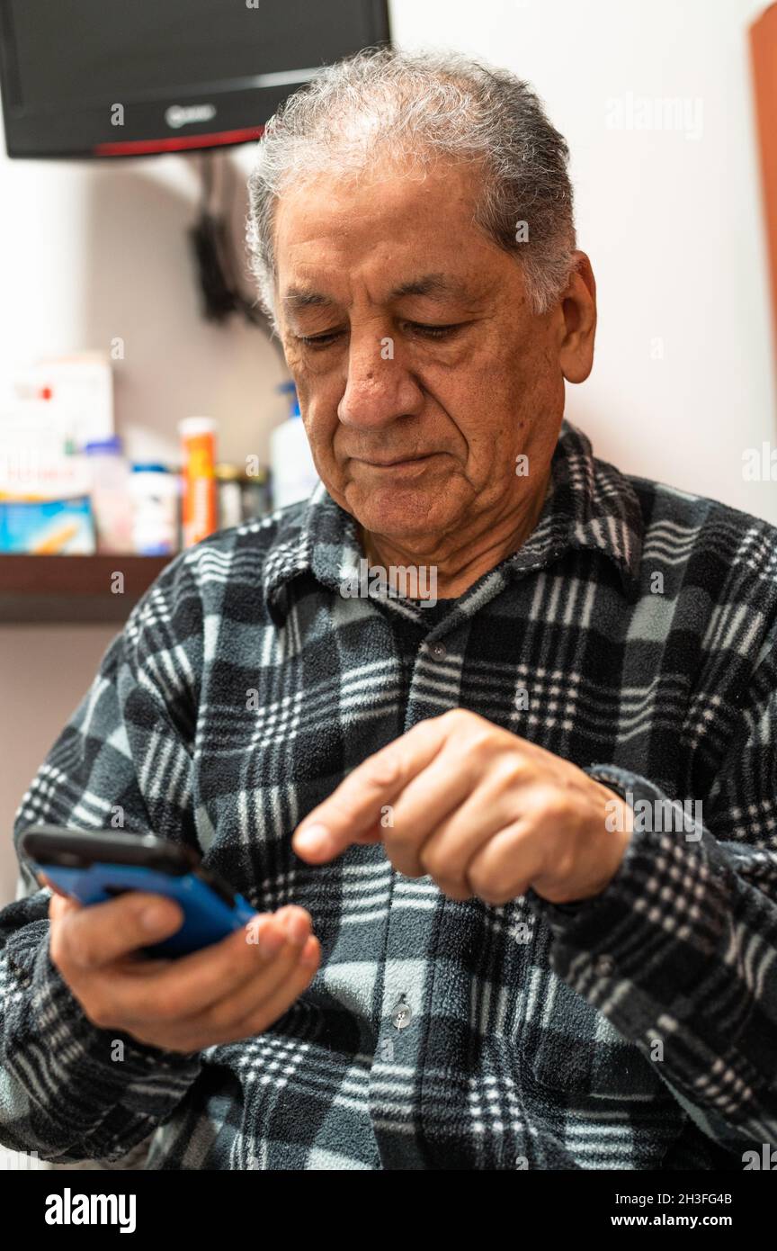 Glücklicher älterer Kaukasischer Mann, der auf den Handybildschirm schaut, um im kabellosen Internet zu surfen. Lächelnd moderne reife 70er Jahre Großvater Text oder Nachricht auf dem Smartphone. Ältere Menschen nutzen zu Hause Zelltechnologien Stockfoto