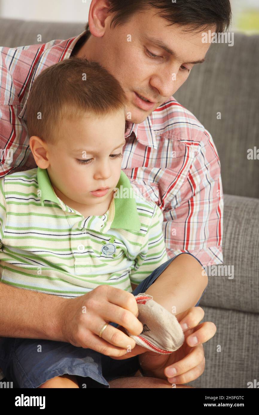 Vater hilft dem Sohn, Socken anzuziehen Stockfoto