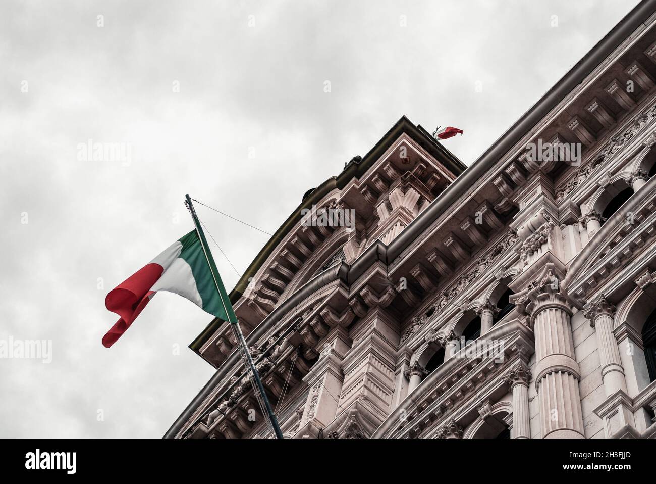 Triest, Italien mit Nationalflaggen mit einem schönen Gebäude und launischer Himmelslandschaft. Stockfoto