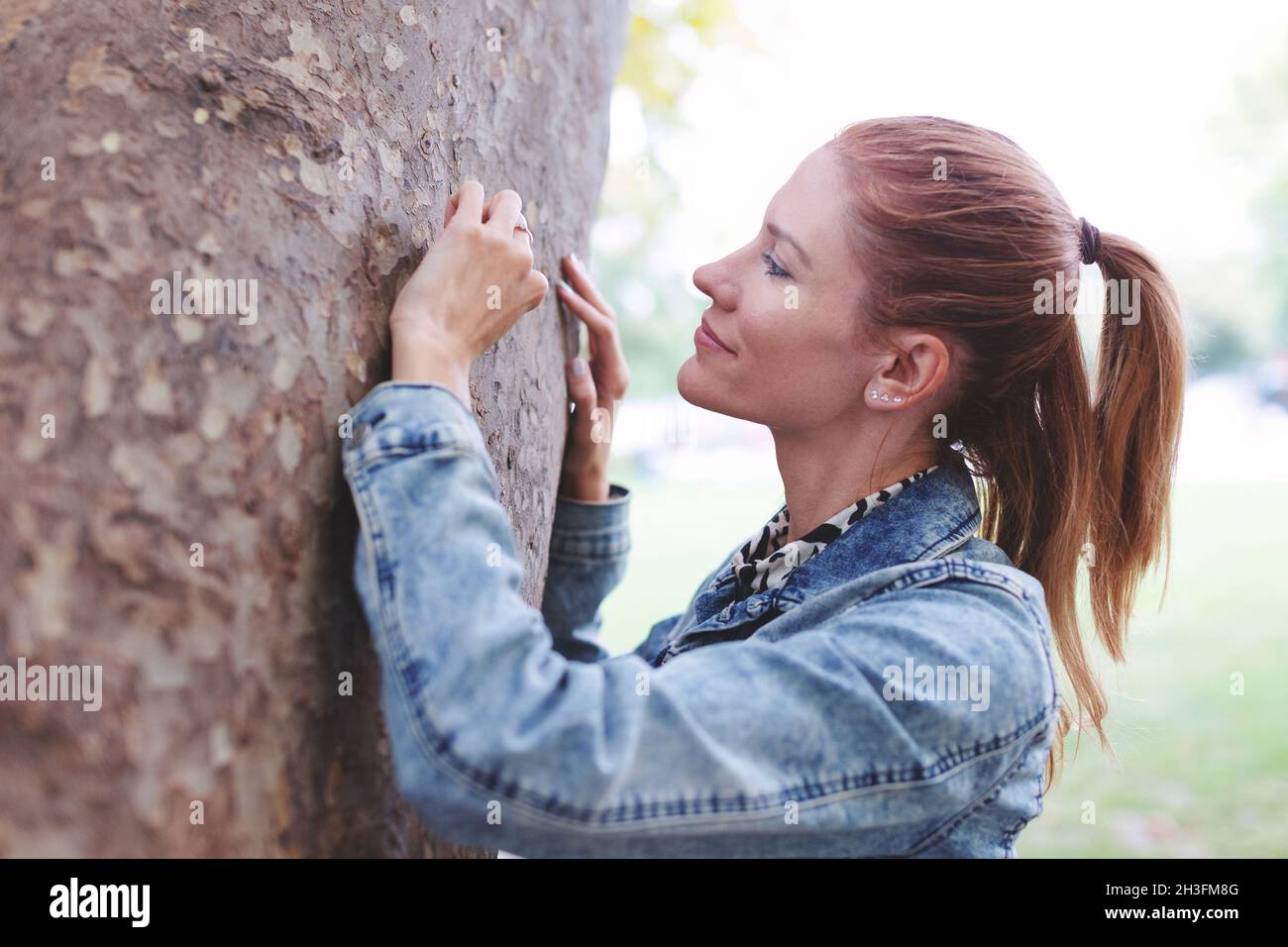 Junge Rotschopf kaukasische Frau Gravur Liebe Zeichen in Baum in der Natur im Herbst Stockfoto