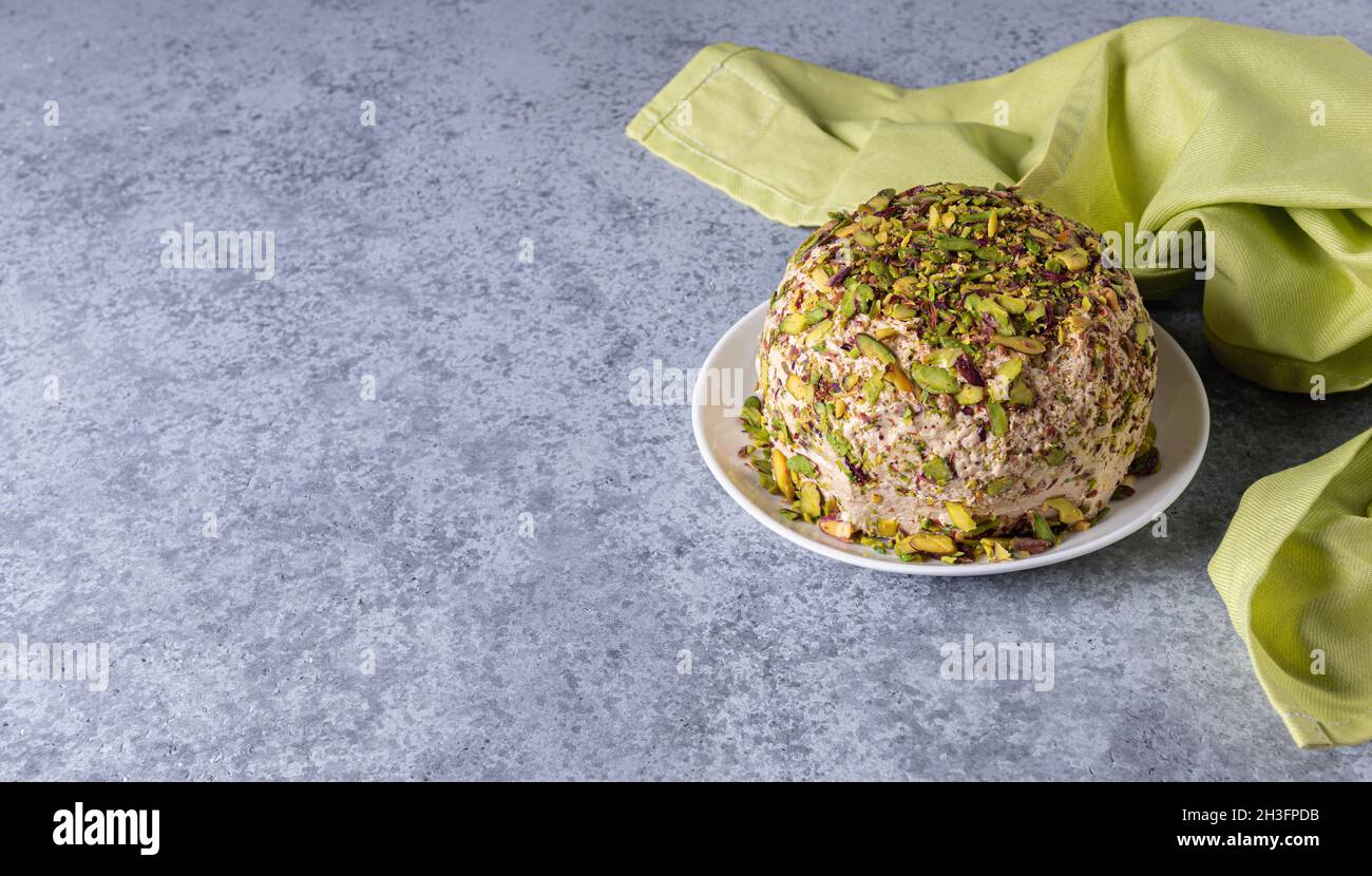 Sesamhalva mit Pistazien-Nüssen auf grauem Hintergrund mit grüner Leinenserviette an der Seite und großem Kopierraum. Türkisches Vergnügen. Traditionell im Nahen Osten Stockfoto