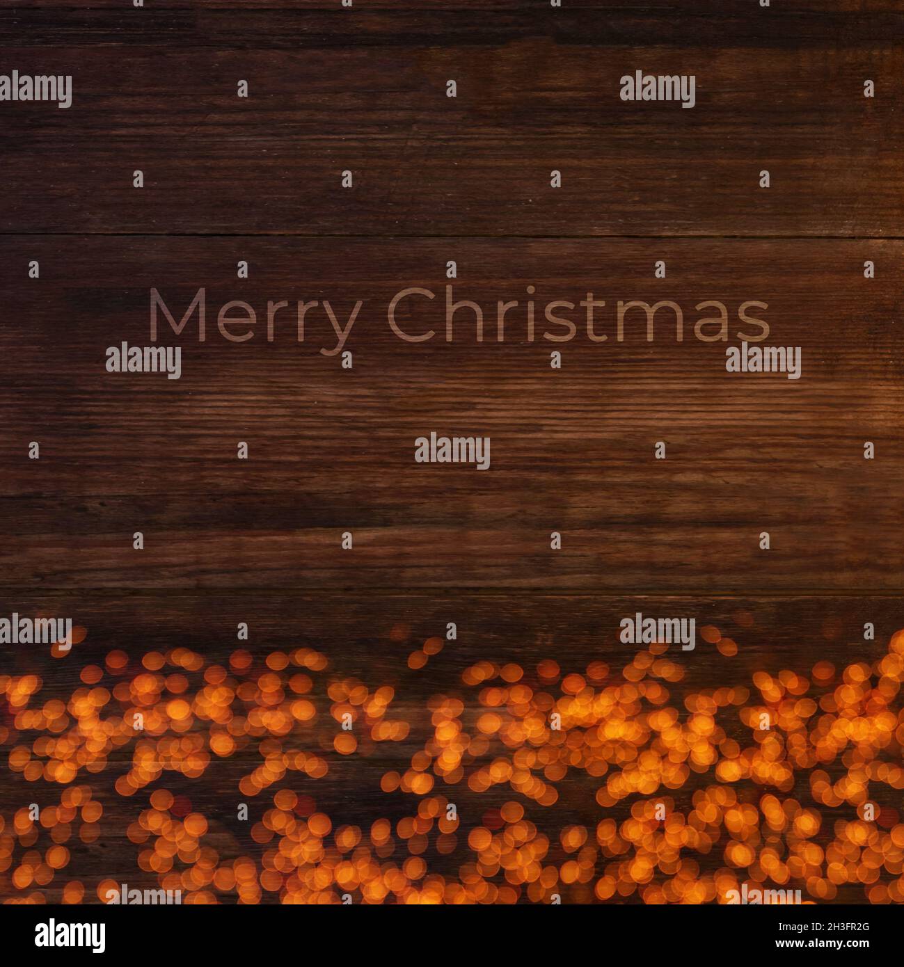 Lichter auf einem hölzernen braunen Hintergrund mit Text Frohe Weihnachten, Weihnachtskarte Stockfoto