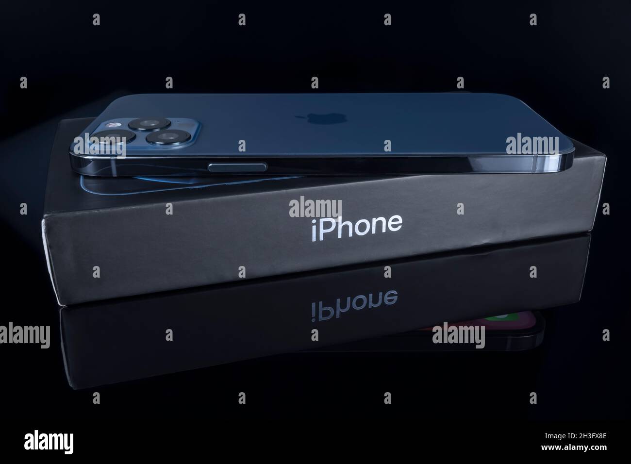 Galati, Rumänien - 14. Oktober 2021: Studioaufnahme des neuen Apple iPhone 12 Pro Max in blauer Farbe über der iPhone-Box. Isolieren auf schwarzem Hintergrund. Illustrative e Stockfoto
