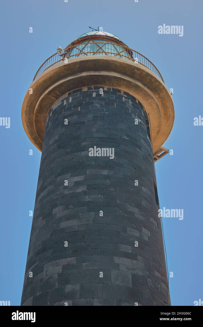 Blick auf den Leuchtturm Punta de Jandia von unten mit dunklem Ziegelturm und Glaskuppel und blauem Himmel im Hintergrund auf Fuerteventura, Kanarische Inseln, Spanien Stockfoto