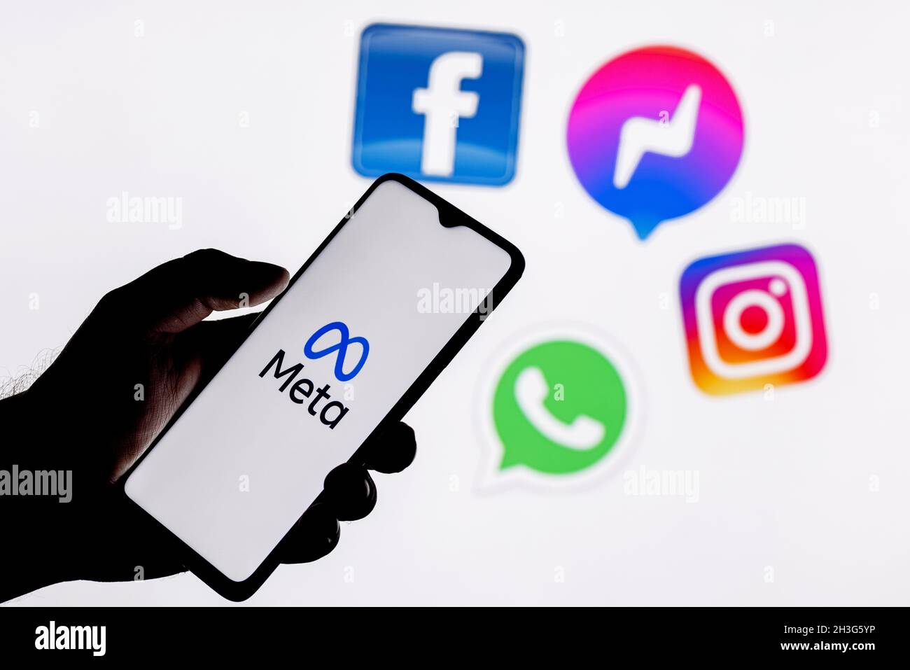 Facebook ändert seinen Namen in Meta. Smartphone mit Meta-Logo auf dem Hintergrund auf Logos von Produkten von facebook Metaverse. Stockfoto