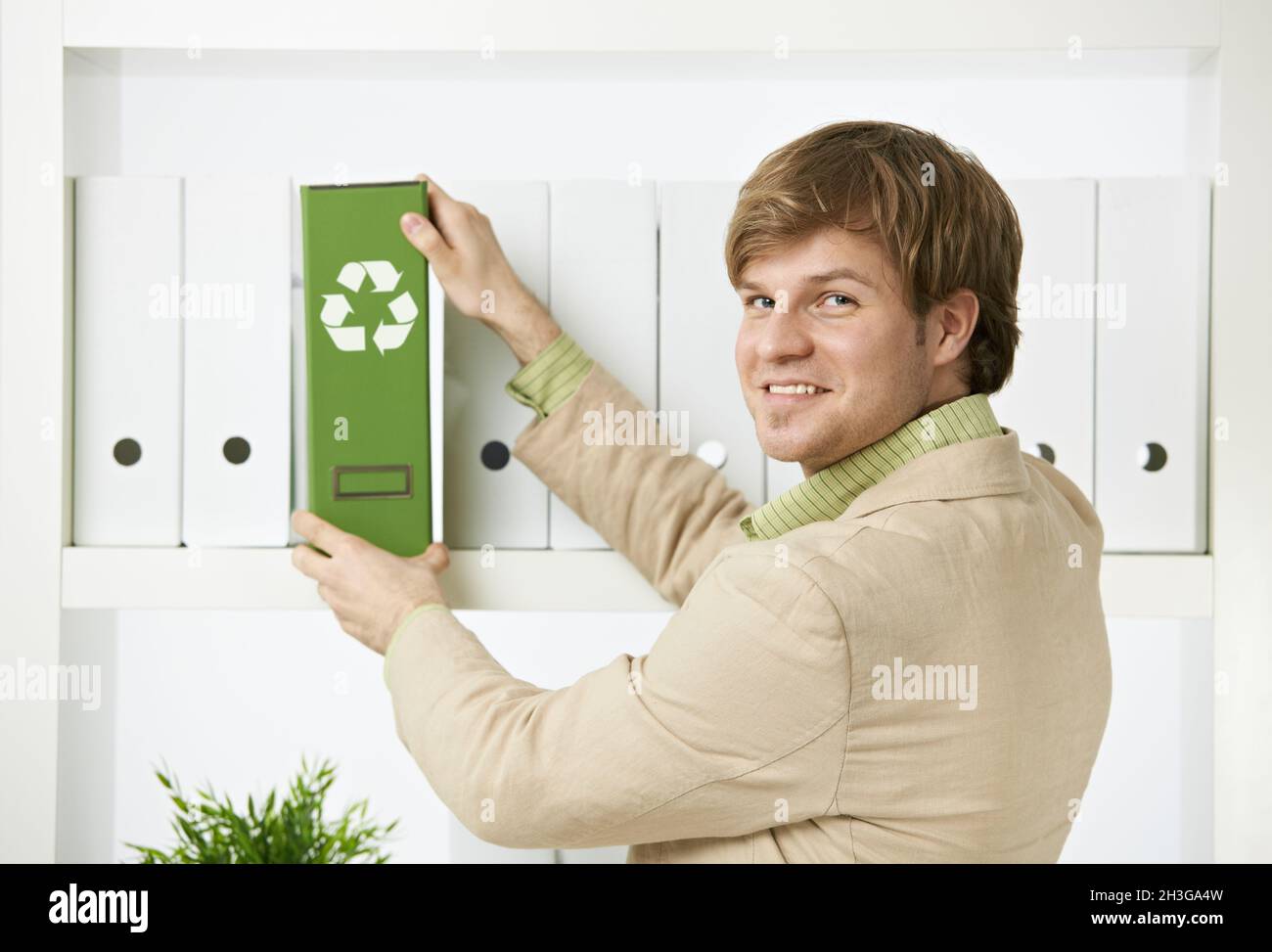 Geschäftsmann entfernt grünen Ordner aus dem Regal Stockfoto